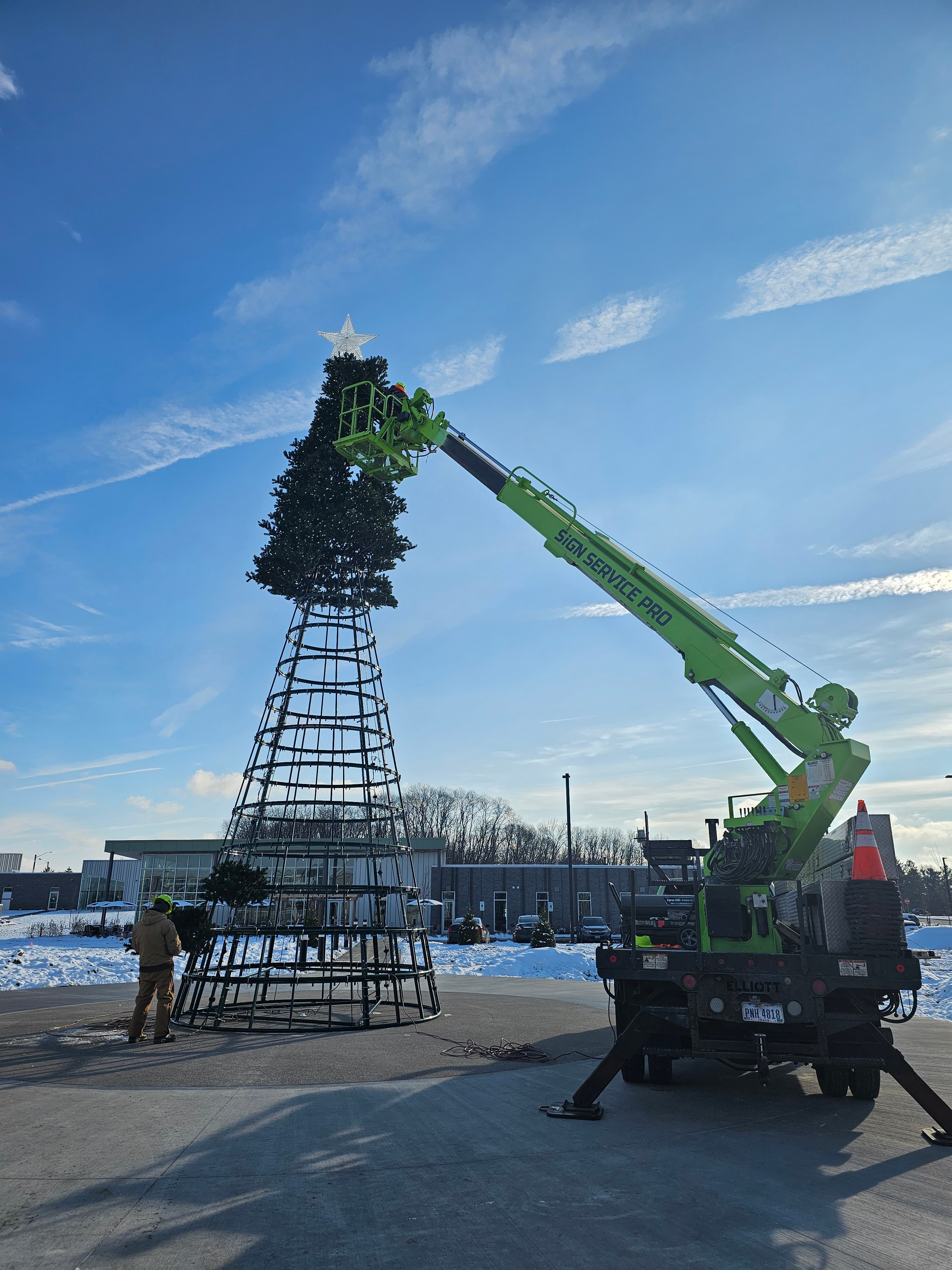 Sign Service Pro crane installing branches on the large artificial Christmas tree