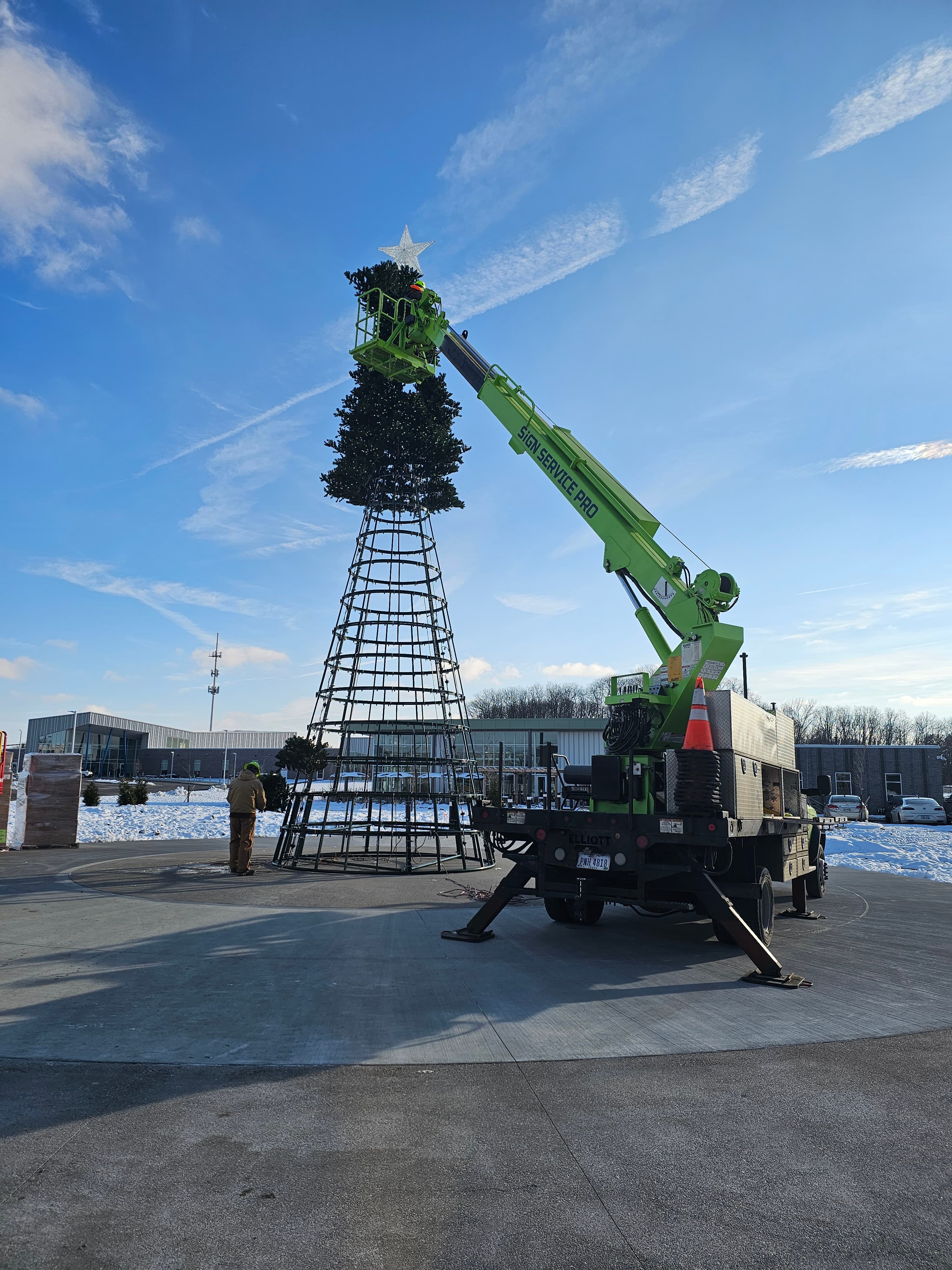 Sign Service Pro crane installing the top of a large artificial Christmas tree