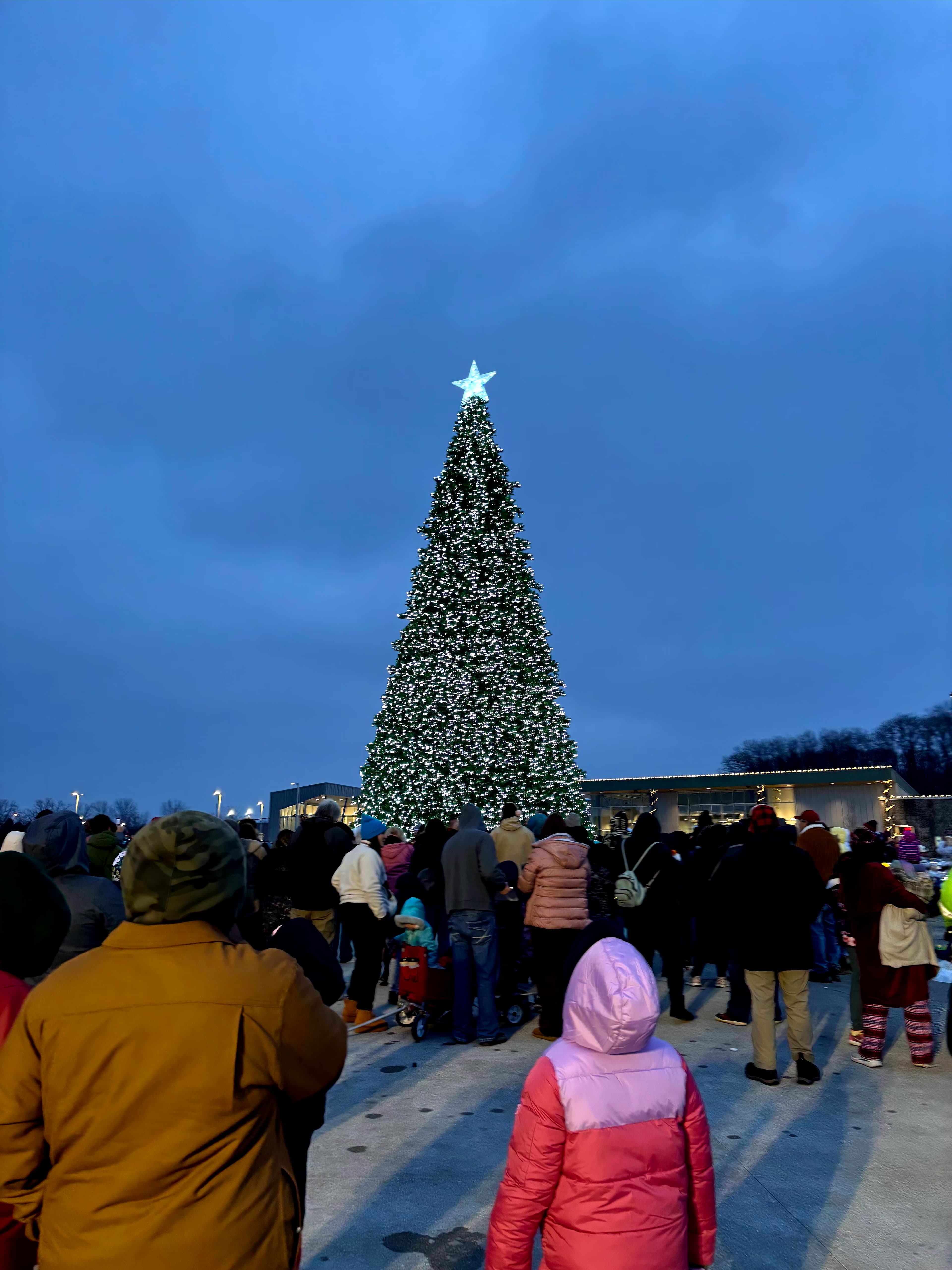 Crowd gathered beneath a large illuminated Christmas tree in Huber Heights