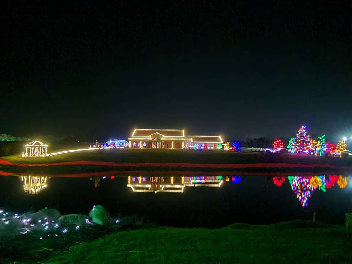 Large commercial property and grounds illuminated with warm-white and colorful holiday lighting