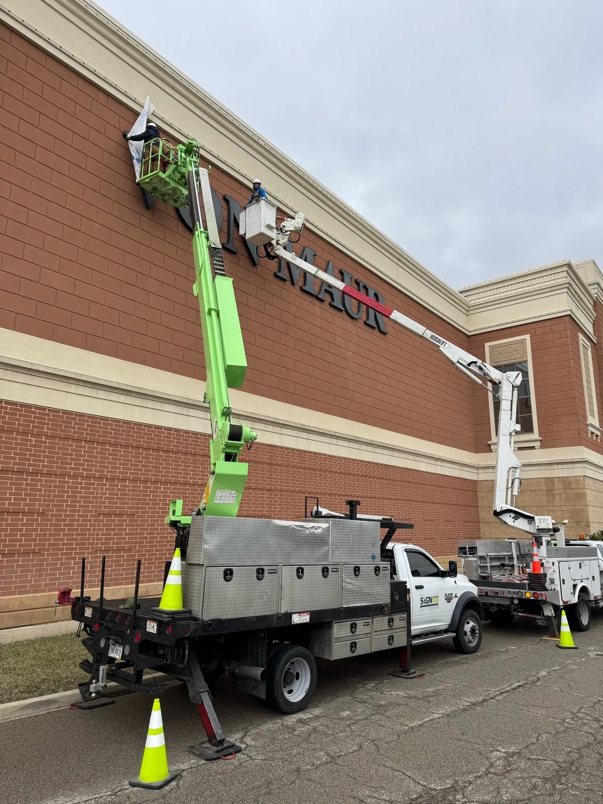 Two aerial crews working on the exterior Von Maur letters in March 2025