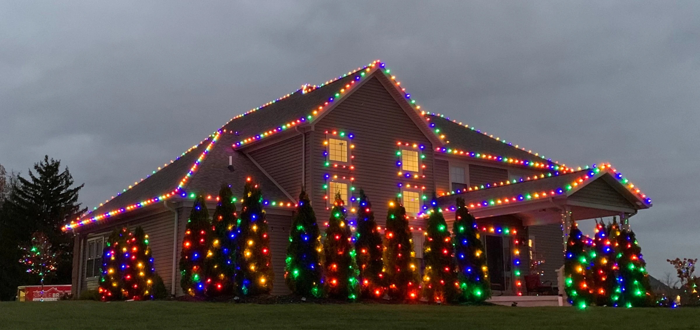 Large home with multicolored roofline, window, and evergreen lighting